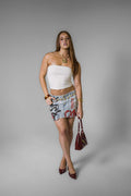 Woman wearing a white top and graffiti red and black skirt on a gray background
