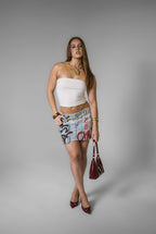 Woman wearing a white top and graffiti red and black skirt on a gray background
